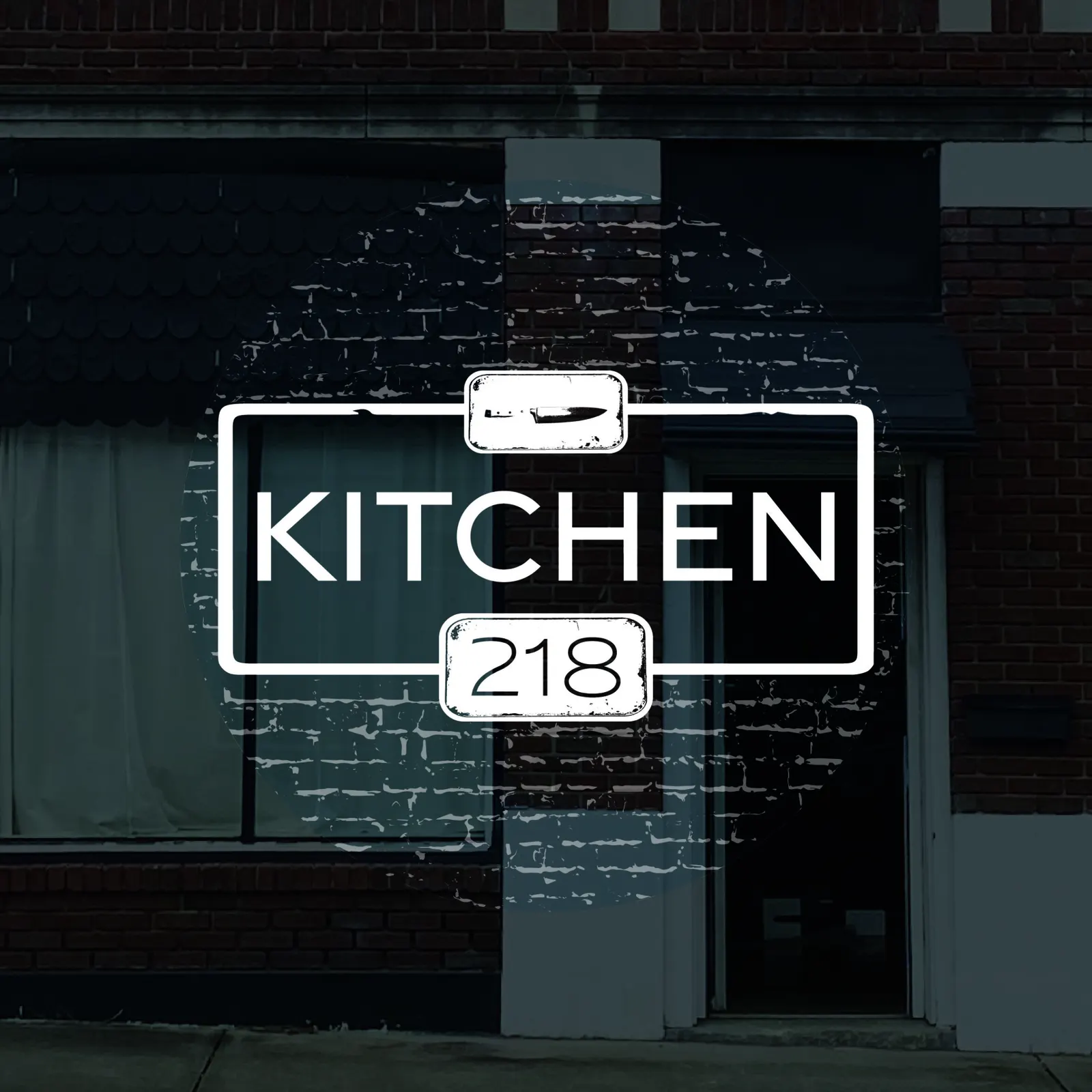 Kitchen 218 logo in white with a chef's knife above and 218 below, over a dark photo of a red brick storefront